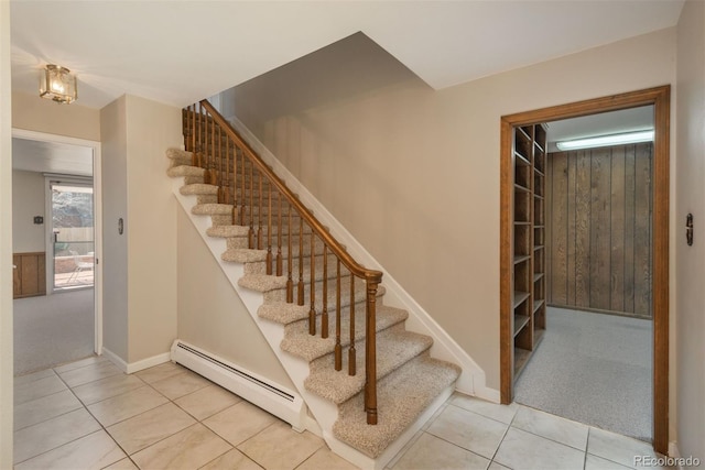 stairs with tile patterned flooring, wooden walls, a baseboard heating unit, baseboards, and carpet floors