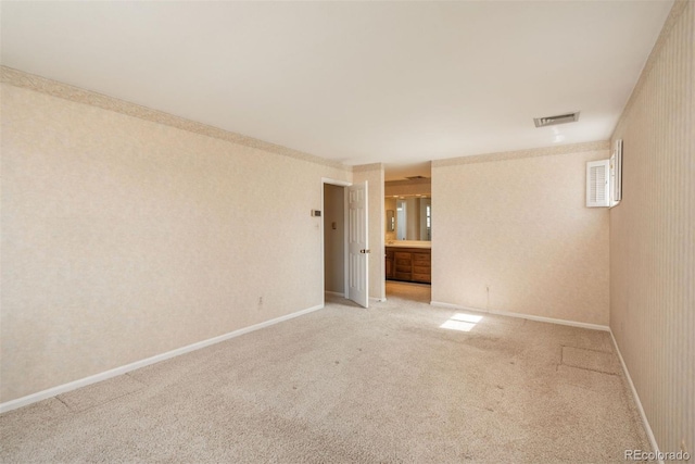 unfurnished room with wallpapered walls, light colored carpet, visible vents, and baseboards