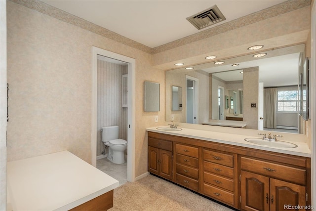 full bath featuring double vanity, toilet, visible vents, and a sink