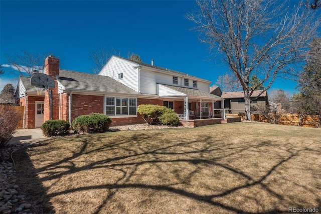 rear view of house with a yard, fence, brick siding, and a chimney