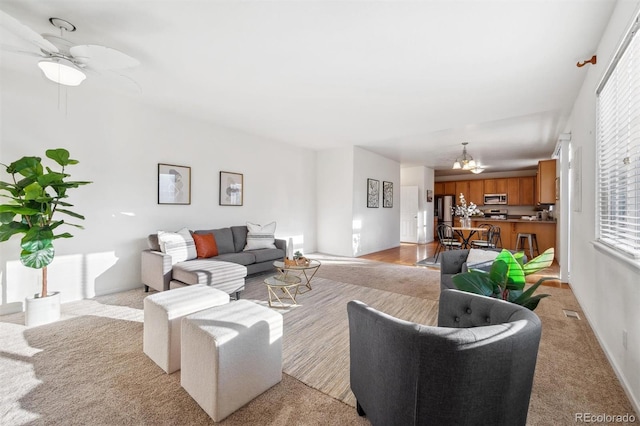 carpeted living room featuring ceiling fan with notable chandelier