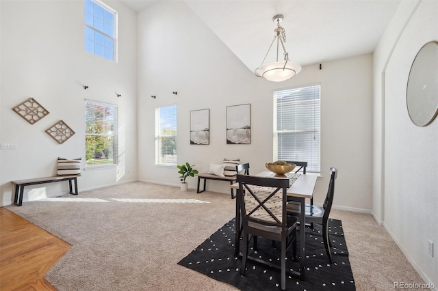 dining room with light carpet and a towering ceiling