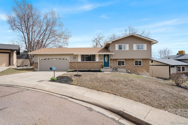 tri-level home with concrete driveway, an attached garage, and brick siding