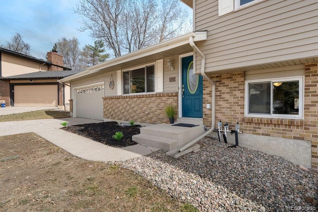 entrance to property with a garage, brick siding, and concrete driveway