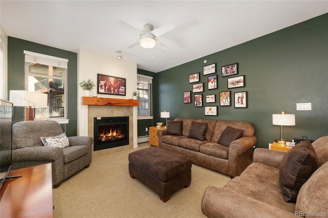 living room featuring ceiling fan, carpet floors, a tile fireplace, and a baseboard radiator