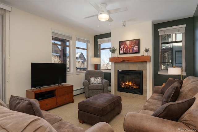 carpeted living room featuring a tiled fireplace, ceiling fan, and a baseboard heating unit