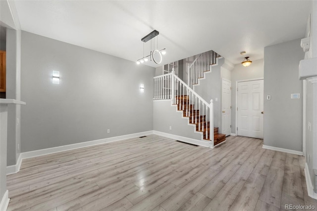 unfurnished living room with light hardwood / wood-style floors and an inviting chandelier