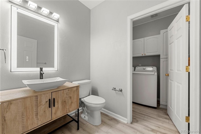 bathroom featuring toilet, vanity, wood-type flooring, and washer / dryer