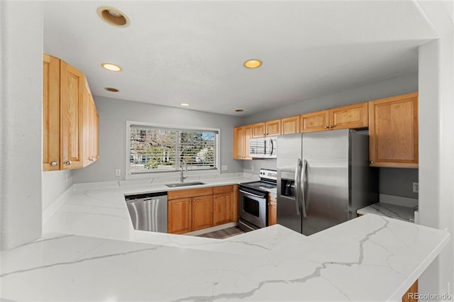 kitchen with kitchen peninsula, appliances with stainless steel finishes, light brown cabinetry, and sink