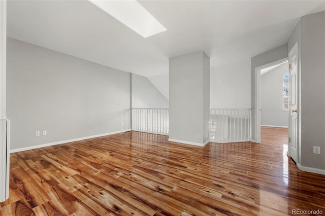 unfurnished living room featuring hardwood / wood-style flooring and a skylight