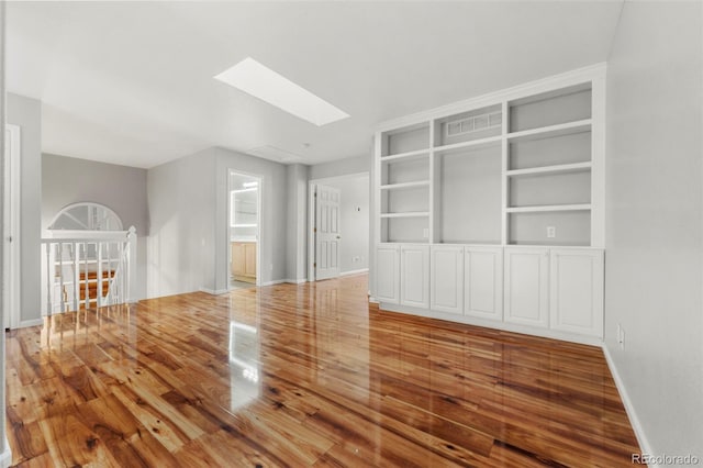 unfurnished living room with a skylight and hardwood / wood-style flooring