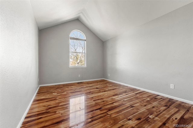 empty room with vaulted ceiling and hardwood / wood-style flooring