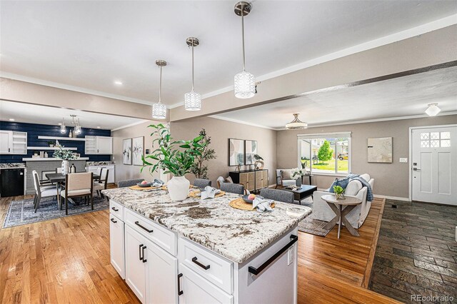 8712 W 64th Way, Arvada, CO 80004 - kitchen with open floor plan, ornamental molding, white cabinetry, light wood-type flooring, and a kitchen island