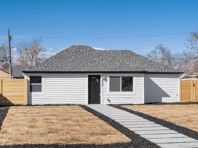 view of front facade featuring fence, a front lawn, and roof with shingles