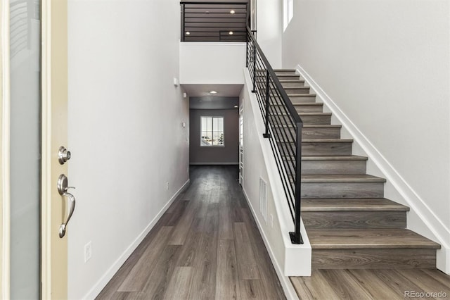 stairway featuring hardwood / wood-style floors and a towering ceiling