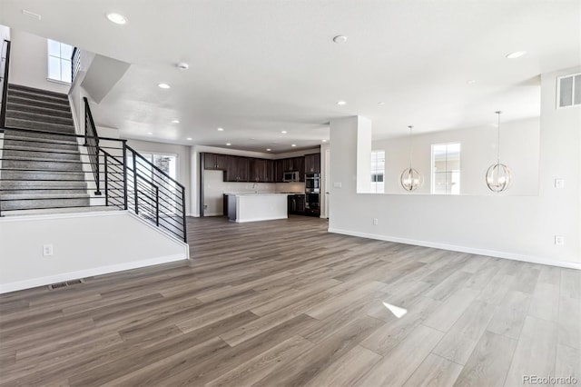 unfurnished living room featuring a notable chandelier and hardwood / wood-style flooring