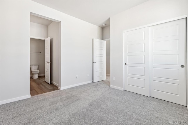 unfurnished bedroom with ensuite bathroom, light carpet, and a closet