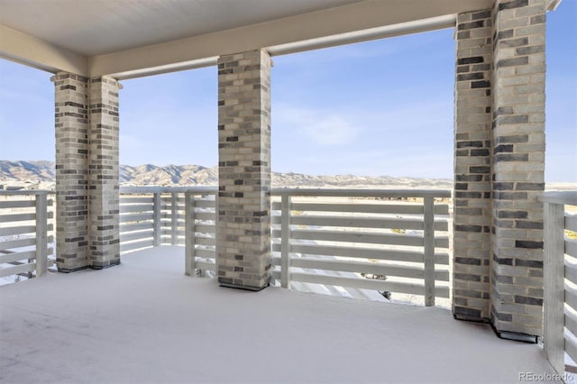 snow covered patio with a mountain view and a balcony