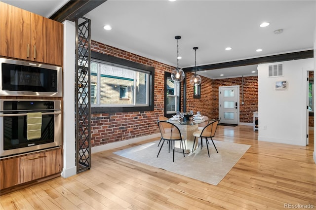 dining space featuring brick wall, beamed ceiling, and light wood-type flooring