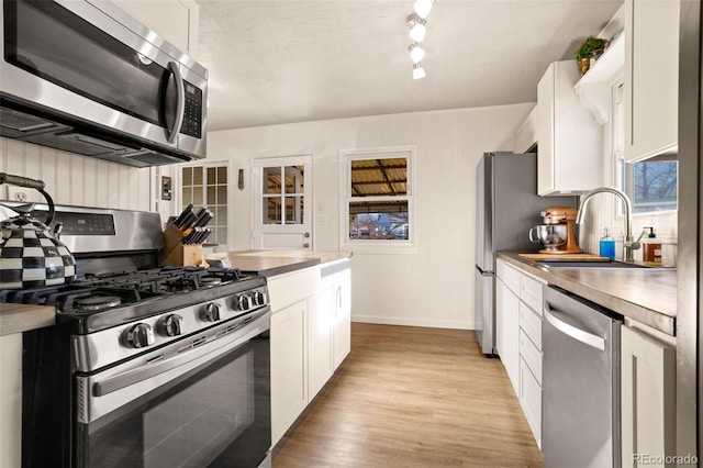 kitchen with sink, white cabinetry, light wood-type flooring, and appliances with stainless steel finishes