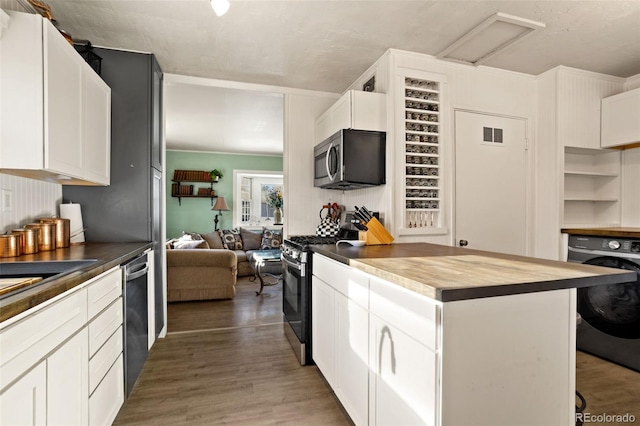 kitchen with butcher block counters, appliances with stainless steel finishes, washer / clothes dryer, white cabinetry, and dark wood-type flooring