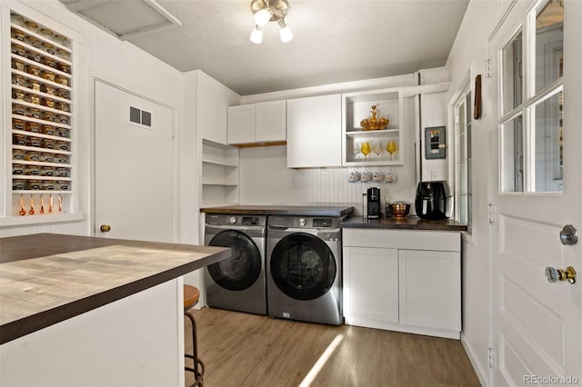 washroom featuring separate washer and dryer, dark wood-type flooring, and cabinets