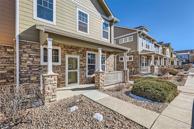 entrance to property featuring stone siding, a residential view, and covered porch