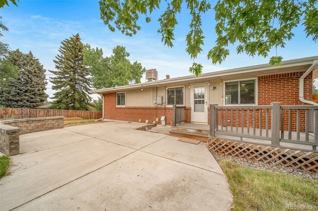 8051 S Kendall Blvd, Littleton, CO 80128 - rear view of house with brick siding, a patio area, a wooden deck, and a chimney