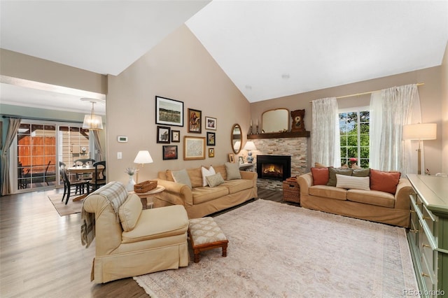 living area featuring high vaulted ceiling, wood finished floors, and a fireplace