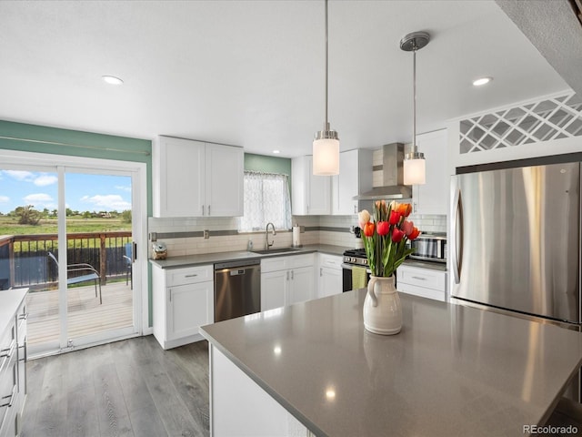 kitchen with wall chimney range hood, appliances with stainless steel finishes, dark countertops, a sink, and recessed lighting