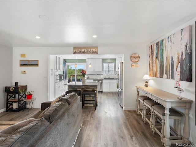 living area with dark wood-style flooring, baseboards, and recessed lighting