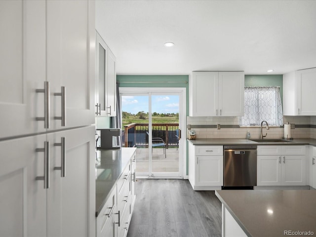 kitchen featuring dishwasher, a sink, decorative backsplash, white cabinets, and healthy amount of natural light