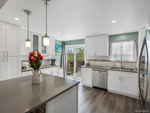 kitchen with dishwasher, a sink, dark countertops, tasteful backsplash, and white cabinets