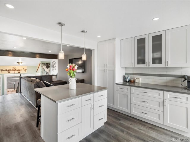 kitchen with dark wood-type flooring, a kitchen breakfast bar, white cabinetry, backsplash, and recessed lighting