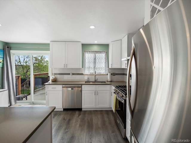 kitchen featuring stainless steel appliances, a sink, decorative backsplash, white cabinets, and plenty of natural light