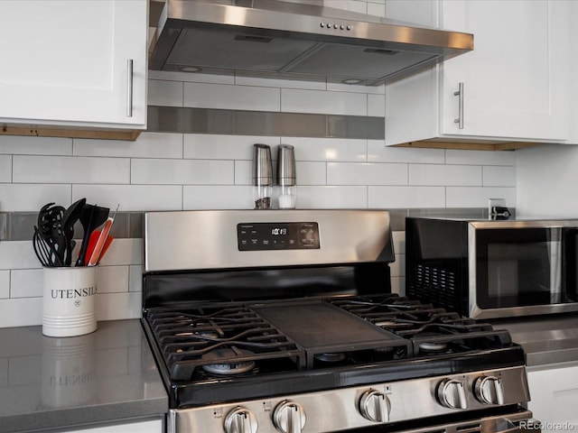 kitchen featuring appliances with stainless steel finishes, wall chimney exhaust hood, white cabinets, and backsplash