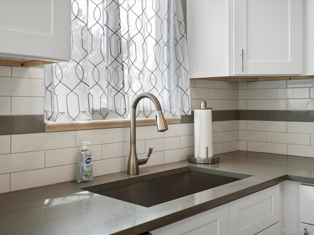 kitchen featuring a sink, backsplash, and white cabinets