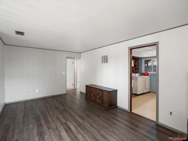 spare room featuring washer and clothes dryer, dark wood-style floors, and baseboards