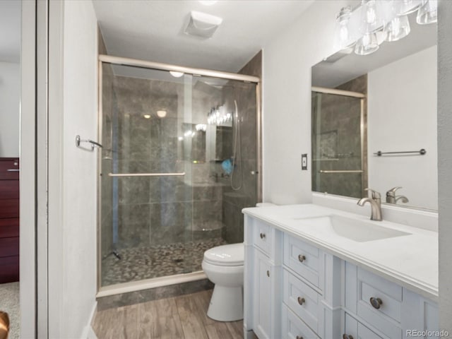 full bath with wood finished floors, a stall shower, toilet, and vanity