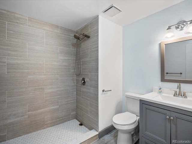 full bath featuring a tile shower, vanity, and toilet