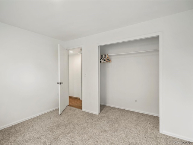 unfurnished bedroom with light colored carpet, baseboards, and a closet