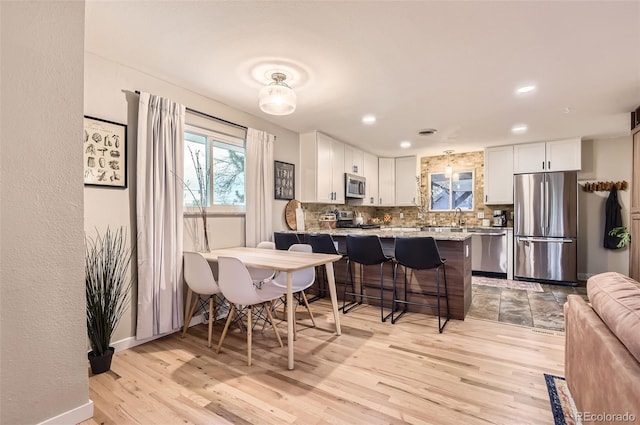 dining room featuring baseboards, a healthy amount of sunlight, and light wood-style floors
