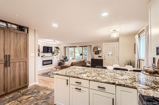 kitchen with light stone counters, recessed lighting, white cabinetry, and range