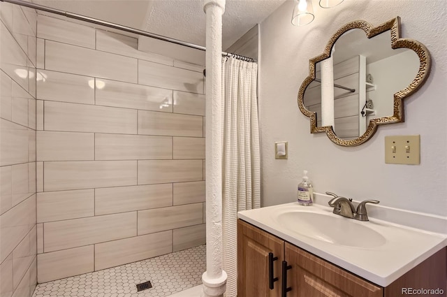 full bathroom with vanity, a textured ceiling, and tiled shower