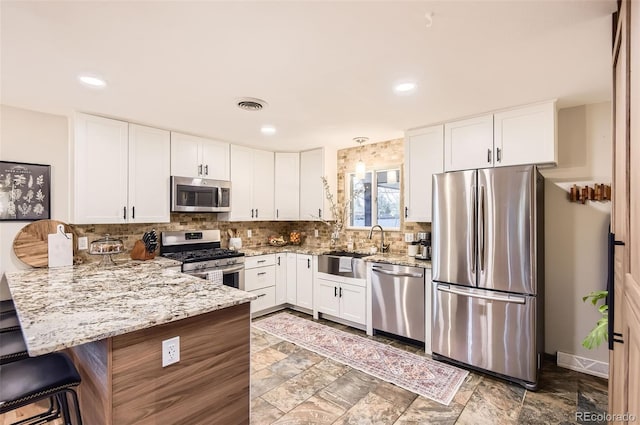 kitchen with a sink, white cabinets, stainless steel appliances, and a peninsula