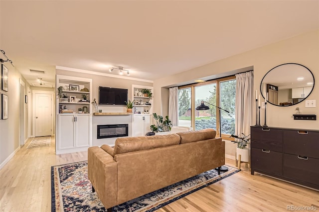 living room with a glass covered fireplace, baseboards, light wood-type flooring, and visible vents
