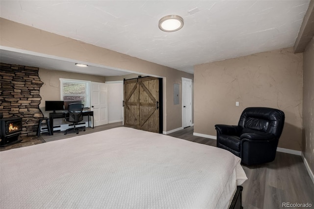 54 Zaza Ln, Evergreen, CO 80439 - bedroom with a barn door, wood finished floors, a wood stove, and baseboards