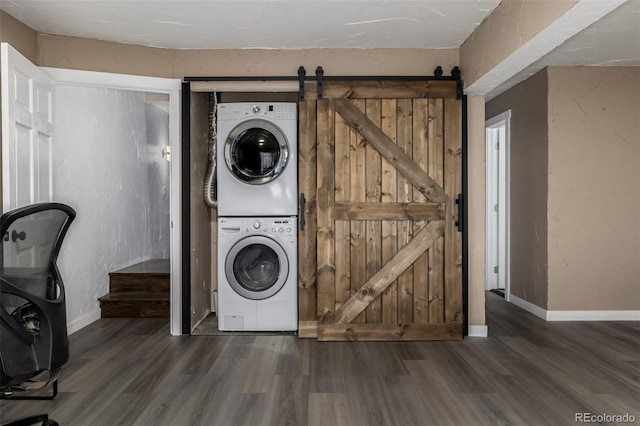 54 Zaza Ln, Evergreen, CO 80439 - washroom featuring estacked washer and dryer, wood finished floors, a barn door, and baseboards