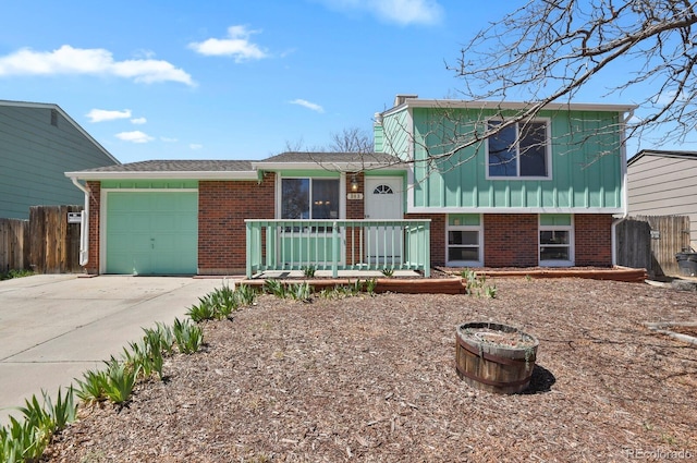 243 Madison Dr, Bennett, CO 80102 - split level home with concrete driveway, board and batten siding, fence, a garage, and brick siding