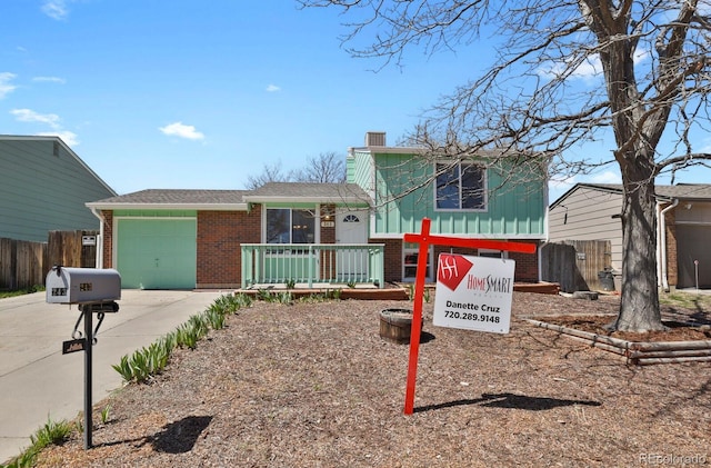 243 Madison Dr, Bennett, CO 80102 - tri-level home with driveway, a chimney, fence, brick siding, and an attached garage